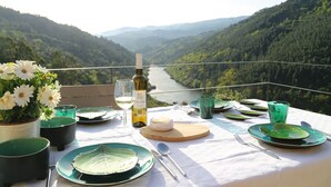 A table set for a meal with a bottle of wine, plates, and cutlery, overlooking a river and forested hills. - Private Pool with fantastic views over Douro River - Porto & Airport 1H (Marco De Canaveses)