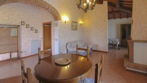 A dining area with a round table, chairs, a chandelier, and a fireplace. - Typical Valdichiana farmhouse in red bricks, near the border between Tuscany and Umbria and a few km (Montepulciano)