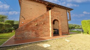 A brick building with a small entrance and a staircase leading up to a door. - Typical Valdichiana farmhouse in red bricks, near the border between Tuscany and Umbria and a few km (Montepulciano)