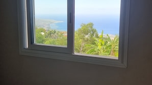 A room with a window overlooking a coastal landscape.