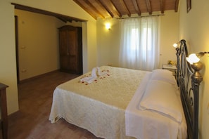 Una camera da letto con un letto, un armadio in legno, un comodino con una lampada e una finestra con tende.
