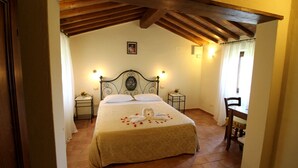 Une chambre à coucher avec un lit, deux tables de chevet, une chaise et une fenêtre avec des rideaux.