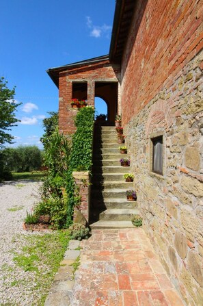 A stone staircase leading to a brick building with a small window and a door at the top.