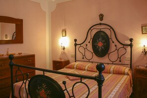 Une chambre à coucher comprenant un lit, une commode, une table de chevet et un miroir fixé au mur.