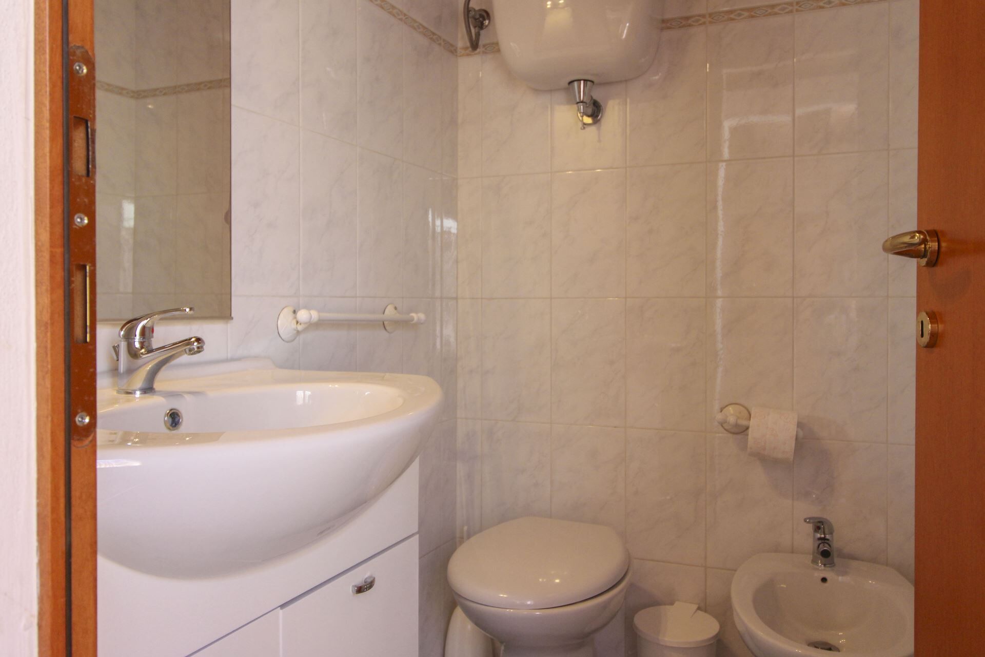 Un baño con lavamanos, inodoro, bidé y espejo.
