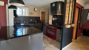 A modern kitchen with a central island, a built-in oven, and a large stove.
