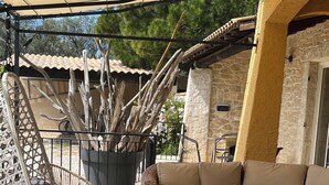 A patio area with a stone table, wicker chairs, a sofa, and a potted plant.