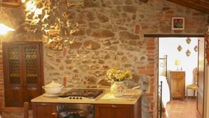 Une cuisine rustique avec un mur en pierre, des armoires en bois et un sol carrelé.