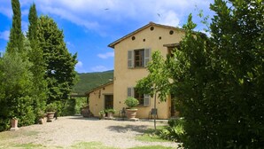 A two-story building with a gravel courtyard, surrounded by greenery and trees. - Villa with private pool, tennis court and table tennis located in Castiglion Fiorentino. Panoramic p (Castiglion Fiorentino)