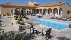 A pool area with lounge chairs and tables, surrounded by a building with arches and a tiled roof. - L'Oasis - a little paradise in Provence, big terrace and pool (Arles)