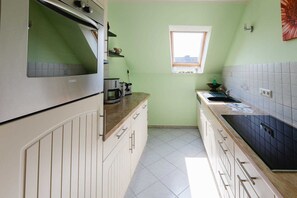 Una cucina con forno a incasso, una finestra e una parete rivestita di piastrelle.