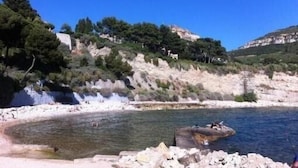 Eine Küstenlandschaft mit felsigem Strand, klarem Wasser und einem Wasserfall.