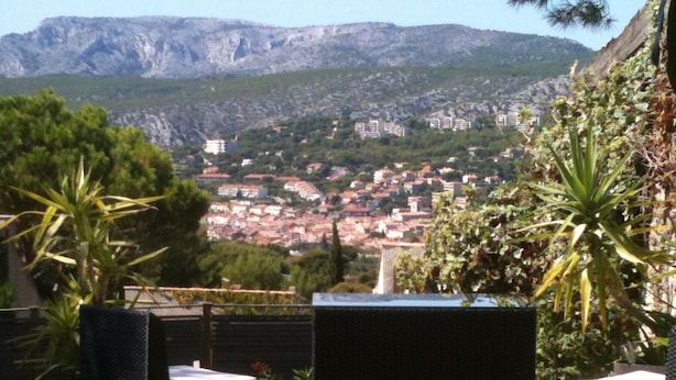 Eine Terrasse mit Korbmöbeln mit Blick auf eine Stadt und Berge.