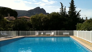 Ein rechteckiger Swimmingpool mit weißem Zaun und Liegestühlen.