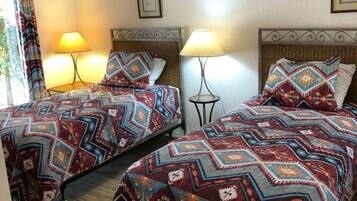 A hotel room with two beds, each with patterned bedding and lamps.