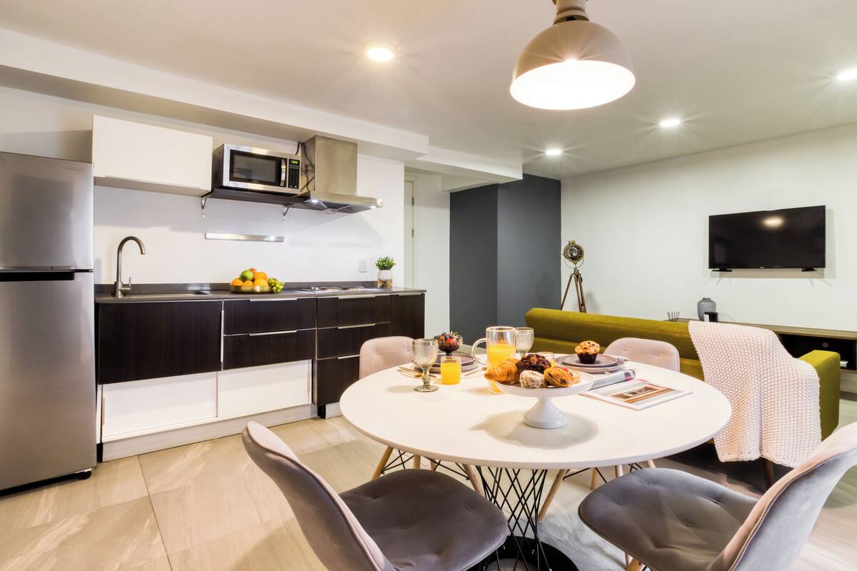 Una cocina moderna con comedor, televisor de pantalla plana y sofá.