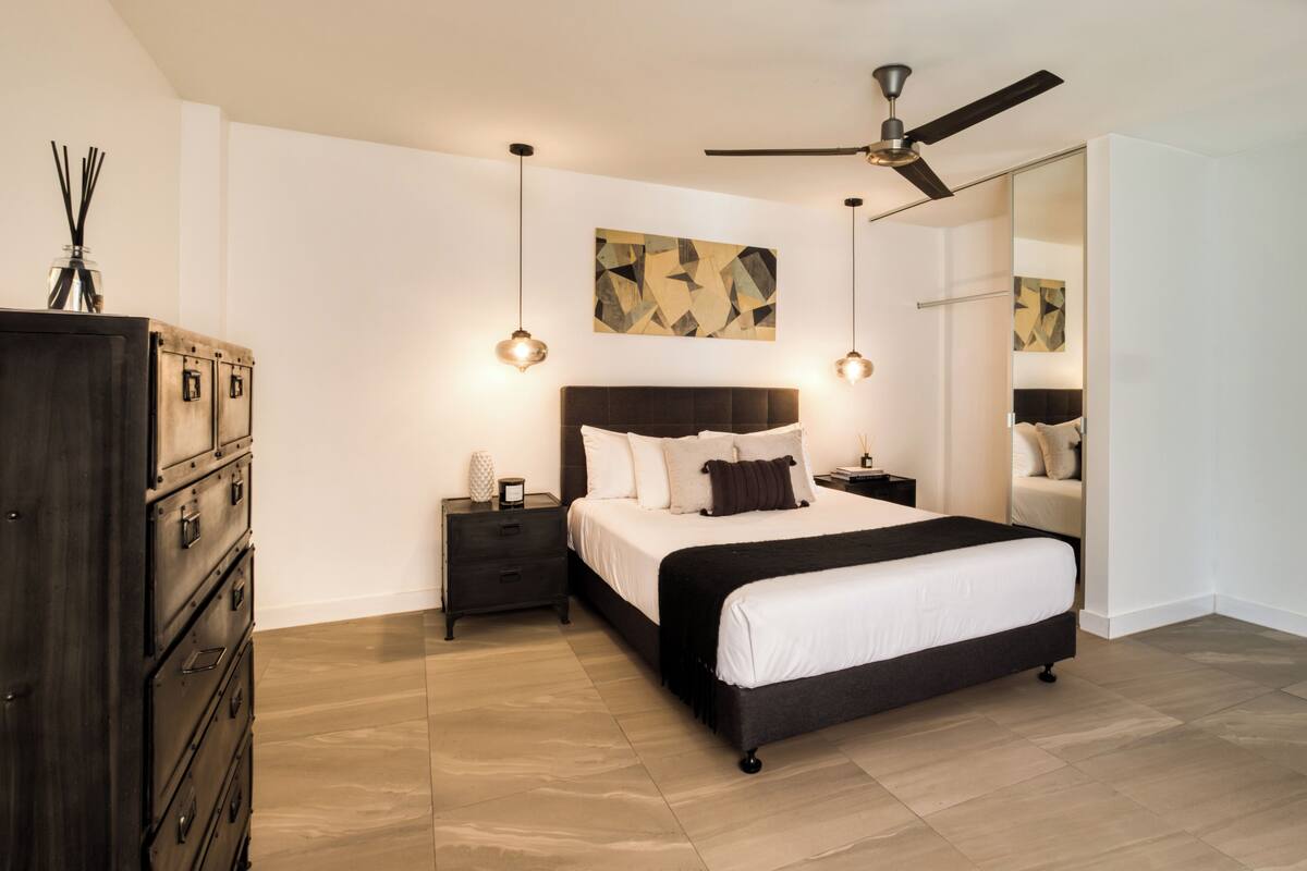 Un dormitorio moderno con una cama grande, un ventilador de techo y un aparador.