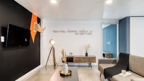 A modern living room with a black and white color scheme, a mounted TV, a wooden console table, and a sofa. - Eazy Centro by ULIV (Tijuana)