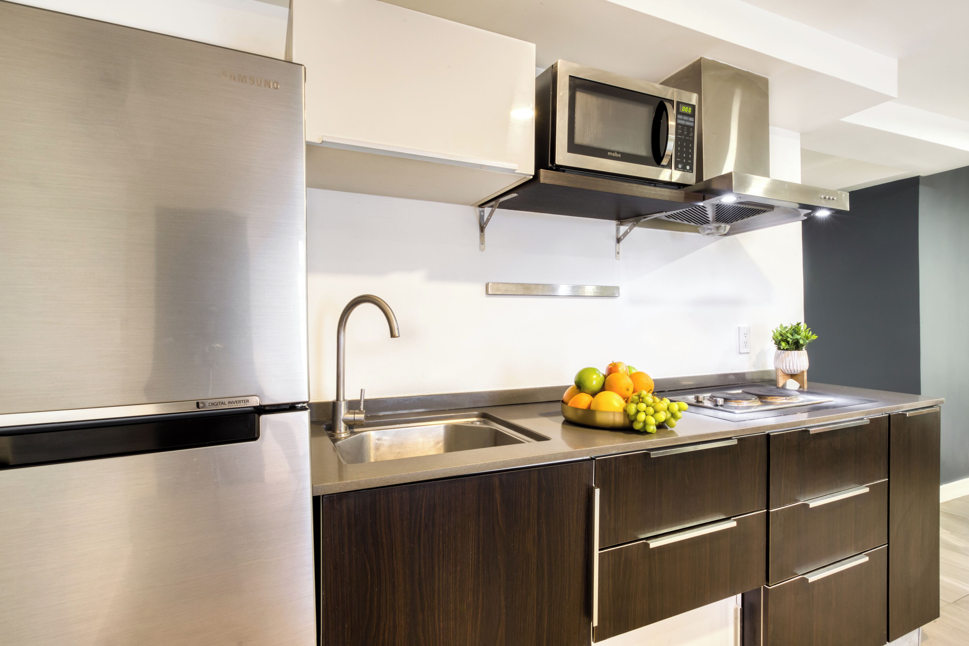 A modern kitchen with stainless steel appliances, a microwave, and a fruit bowl on the counter.
