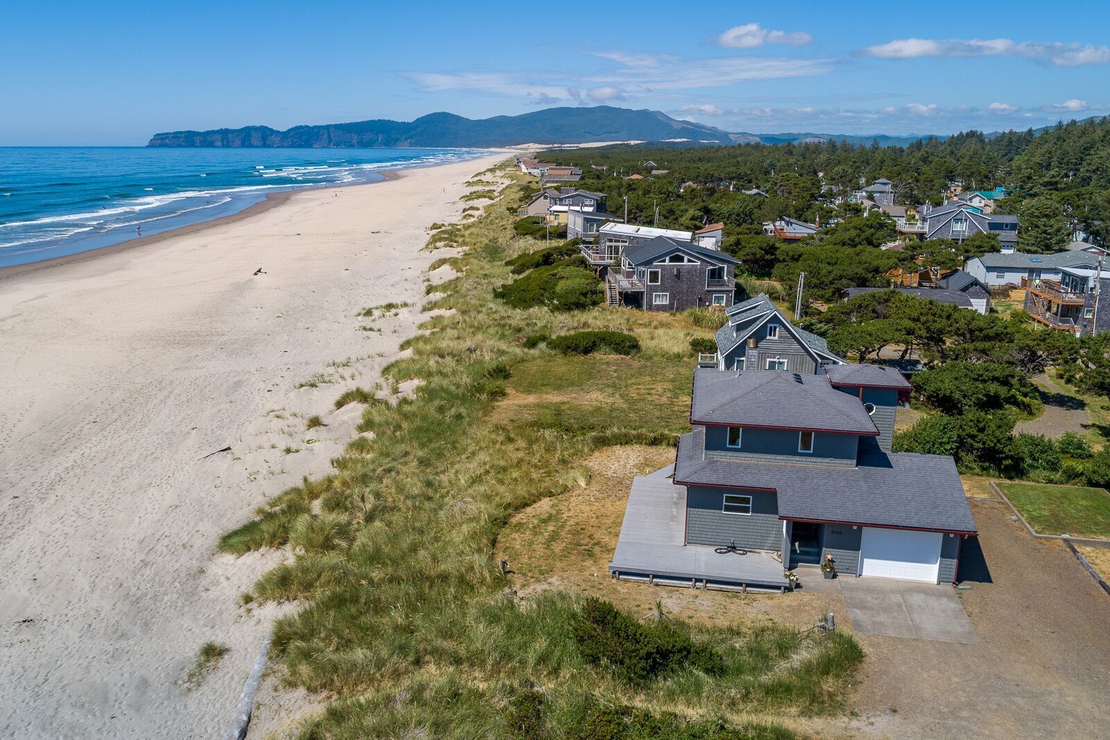 A coastal residential area with houses adjacent to a sandy beach and ocean.