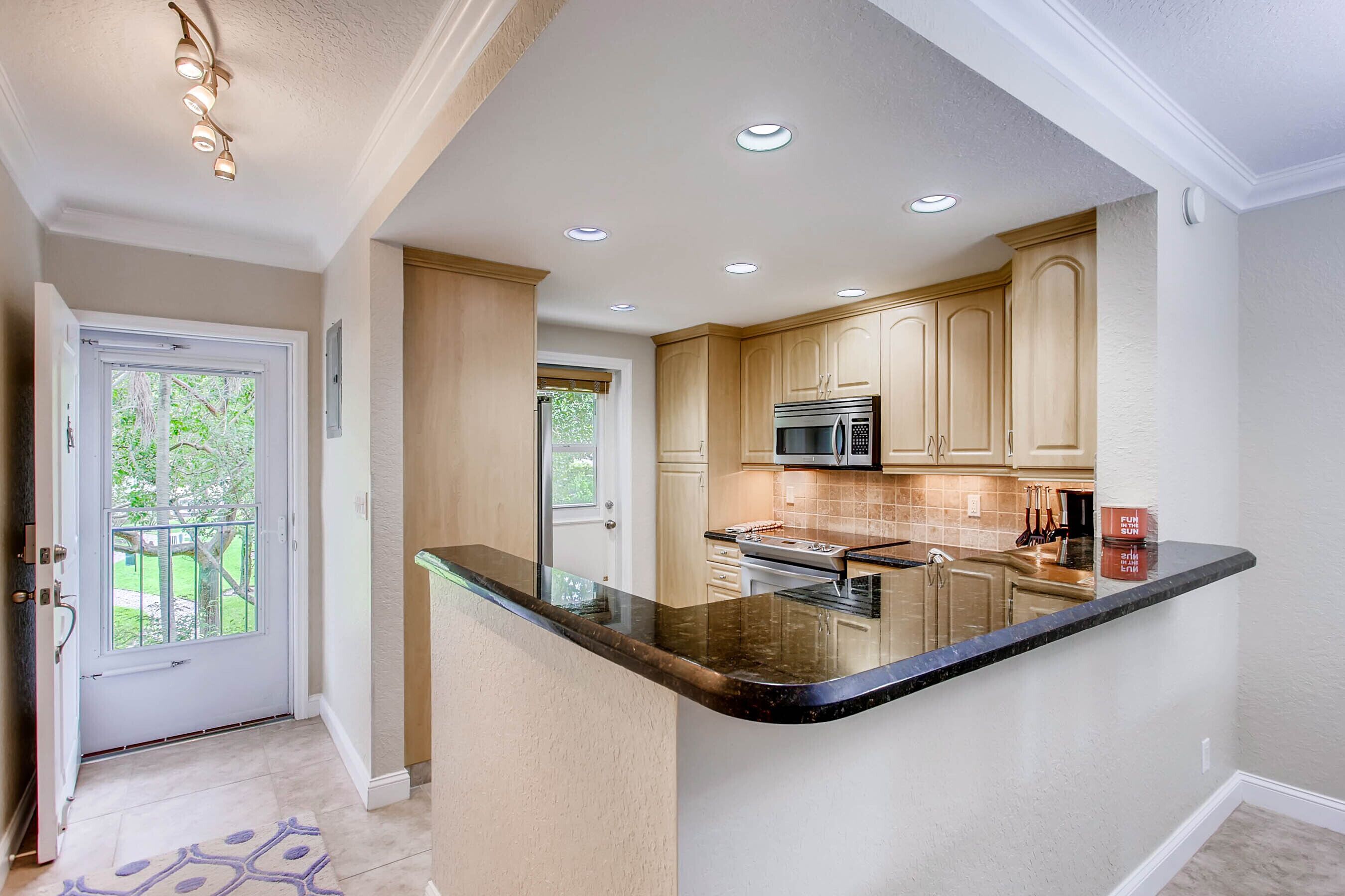 A kitchen with a central island, recessed ceiling lights, and wooden cabinets.
