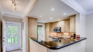A kitchen with a central island, recessed ceiling lights, and wooden cabinets.