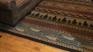 Una habitación acogedora de estilo cabaña con dos sofás, una alfombra estampada y paredes de madera.