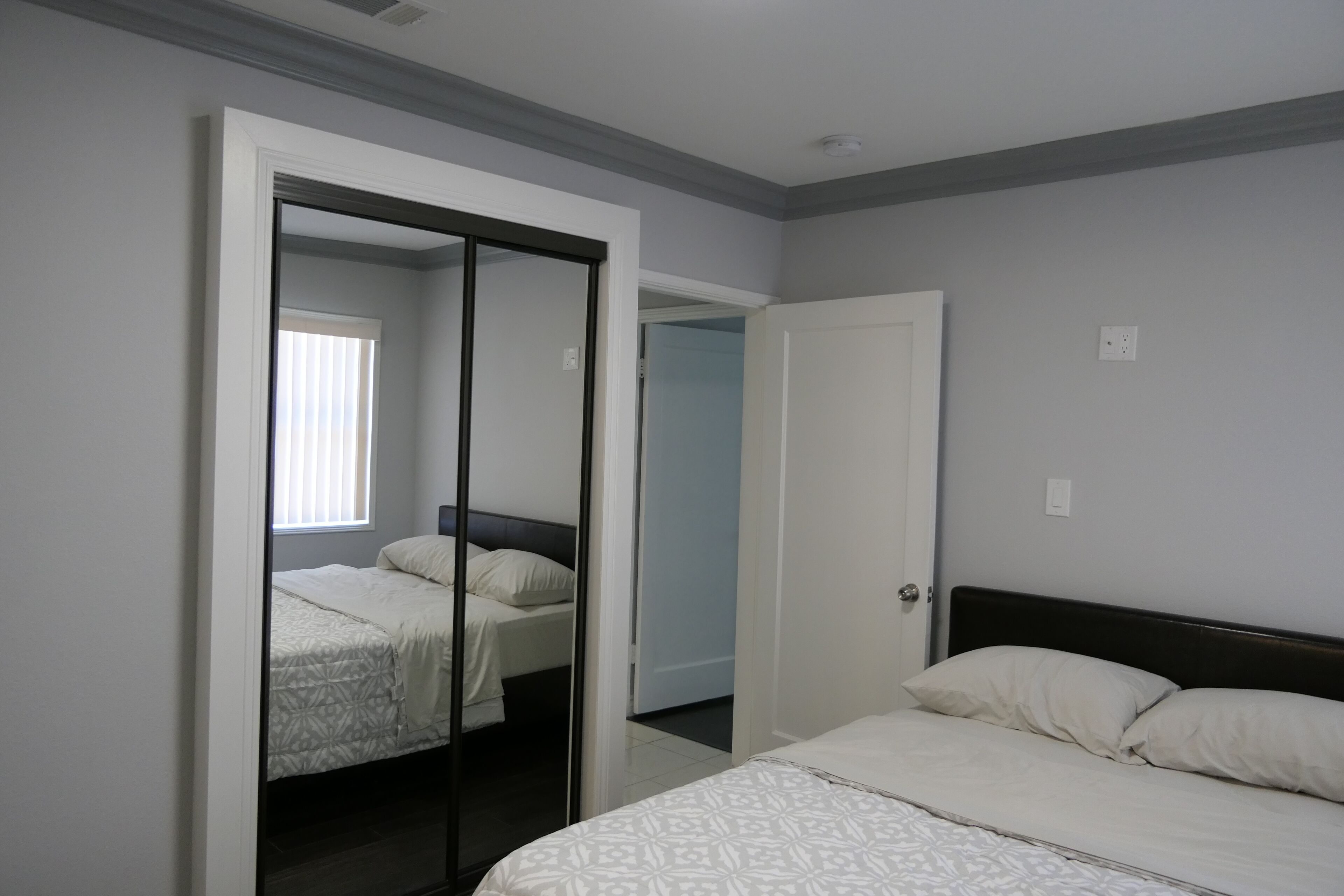 Une chambre à coucher comprenant un lit, une armoire et une porte donnant sur une autre pièce.
