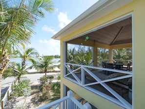 A covered outdoor area with a view of the beach and palm trees.