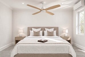 A bedroom with a bed, two bedside tables with lamps, a ceiling fan, and a window.