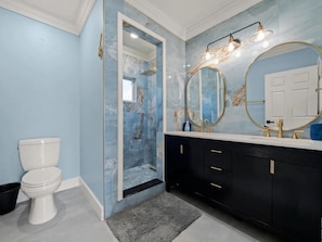 A bathroom with a white toilet, a black vanity with gold fixtures, and a large mirror with a gold frame.