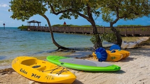 A beach with a wooden pier, a gazebo, and inflatable water toys. - Reel Large END Unit in Ocean Pointe Suites - Newly Renovated! (Tavernier)