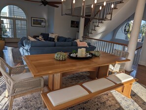 A spacious living room with a wooden dining table, wicker chairs, and a blue sofa.