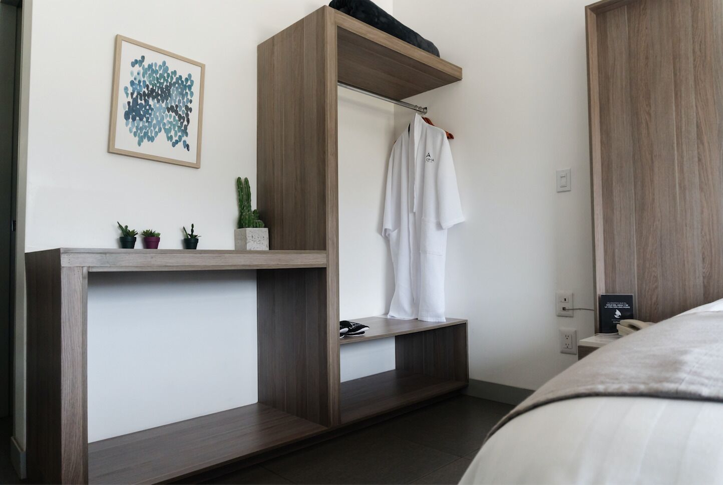 Un dormitorio moderno con un tocador de madera integrado, cortina de ducha colgante y una pequeña planta en maceta sobre el tocador.