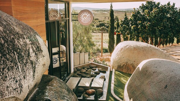 Un espacio al aire libre moderno con grandes rocas, un sendero de piedra y vistas al campo.