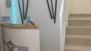 A reception desk with a logo, a wall-mounted light strip, and a staircase.