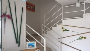 A staircase with white railings and a wooden handrail, leading to an upper floor.