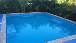 A rectangular swimming pool with a tiled edge, surrounded by a blue deck.