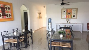 A dining area with two glass-top tables, black metal chairs, and woven cushions.