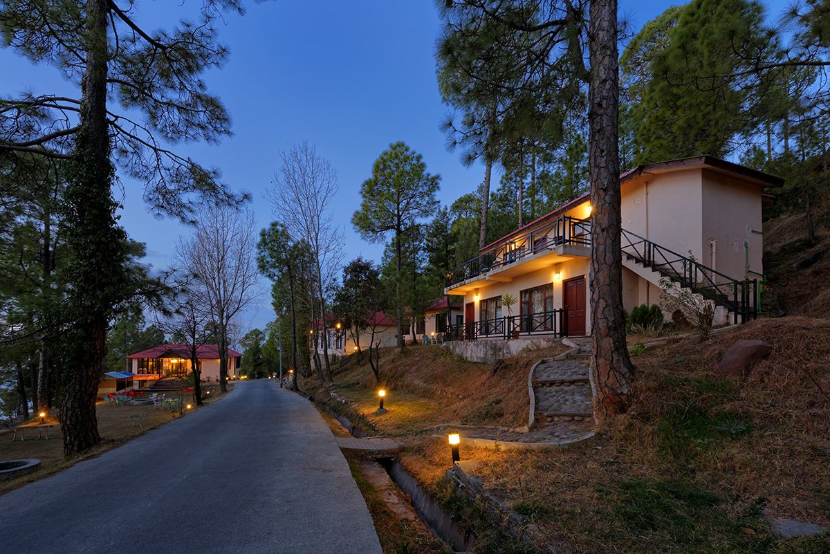 A two-story house with a balcony, surrounded by trees and a clear sky.