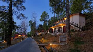 A two-story house with a balcony, surrounded by trees and a clear sky.