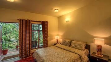 Un dormitorio con una cama grande, dos lámparas de noche, una ventana con cortinas y vistas a zonas verdes.