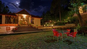 Una casa de dos plantas con porche cubierto, mobiliario exterior y una entrada bien iluminada.