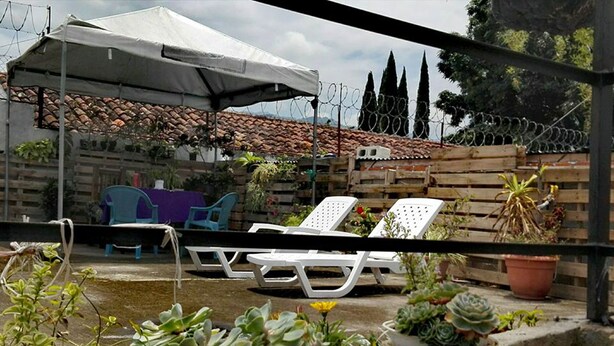 A patio area with a white umbrella, lounge chairs, and potted plants. - Casa de Leon (Antigua Guatemala)