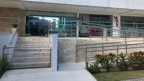 Une entrée moderne, avec une façade en verre, des garde-corps en métal et un revêtement extérieur en carreaux.