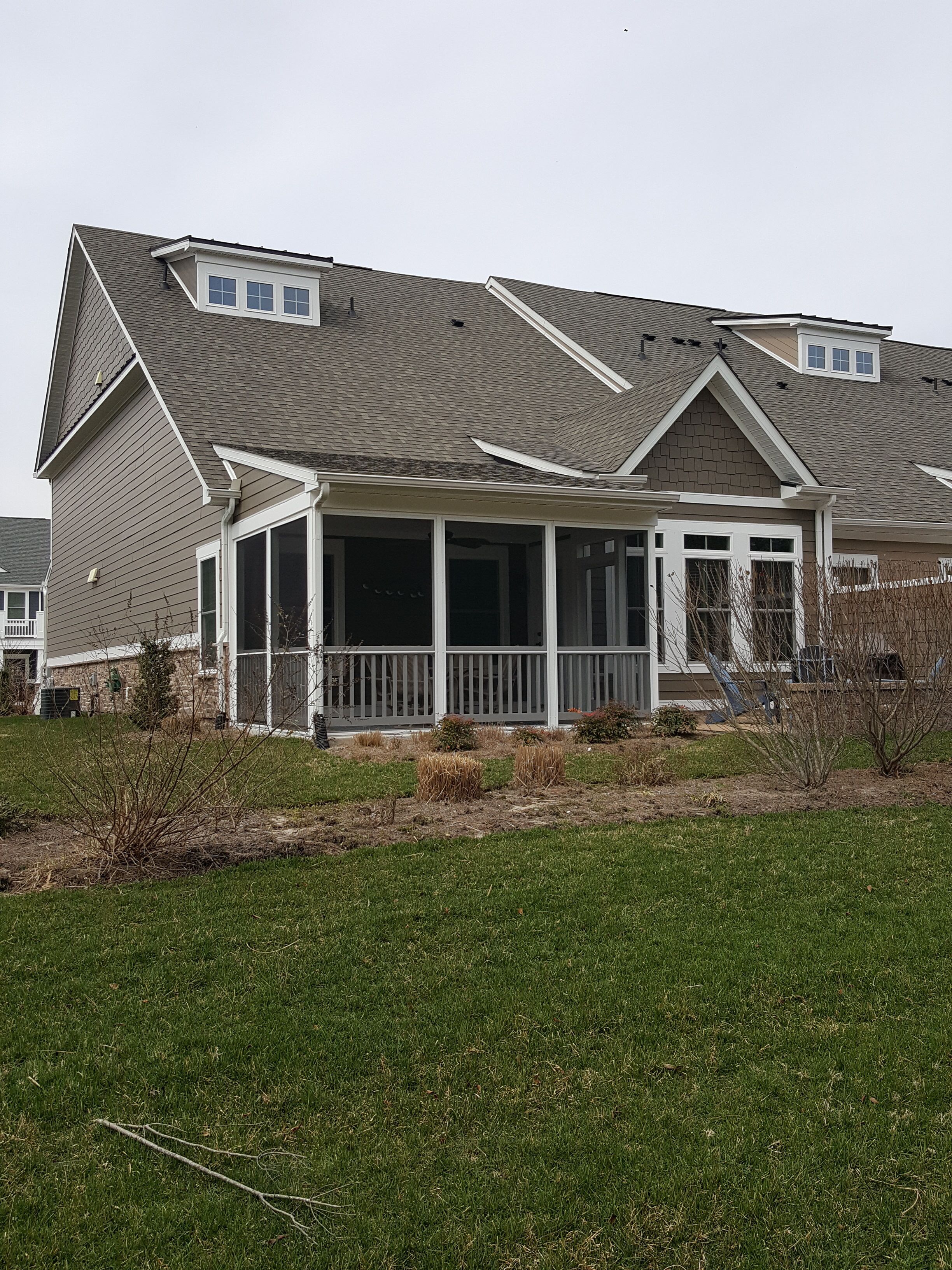 A two-story house with a covered porch, a small deck, and a sloped roof.