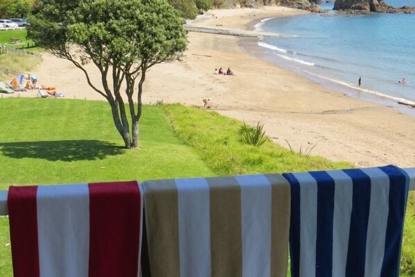 A beach with a grassy area, a tree, and a view of the sea.