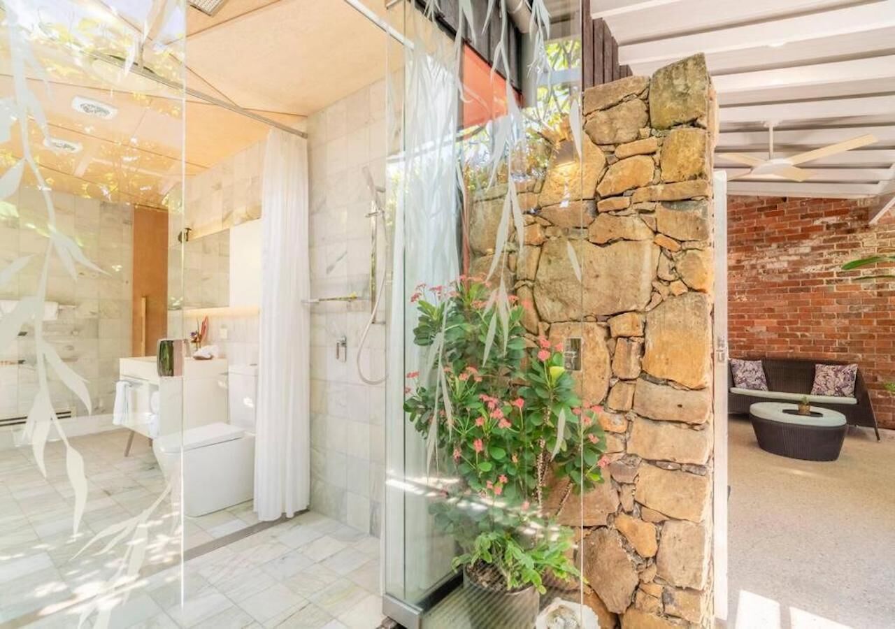 Une salle de bain moderne avec une douche à parois de verre, un mur d’accent en pierre et un espace lavabo bien visible.