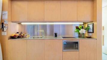 A compact kitchen with a stainless steel sink, a built-in oven, and a microwave.