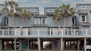 A multi-story residential building with a covered parking area, palm trees, and a balcony. - Spacious condo with sleeping loft - Sleeps 10 on Pensacola Bay - San Deluna 29 (Pensacola Beach)